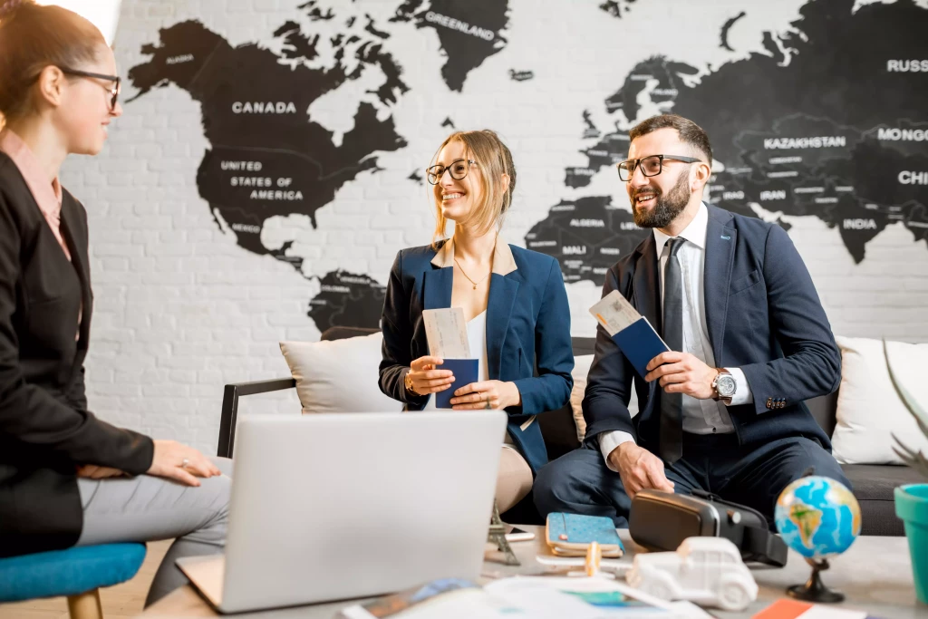 young-businesscouple-choosing-trip-with-agent-sitting-travel-agency-office-with-world-map-background